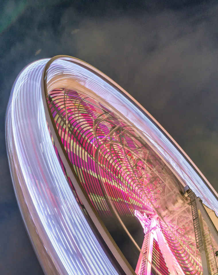 Industries We Serve: illuminated Ferris wheel in motion at dusk