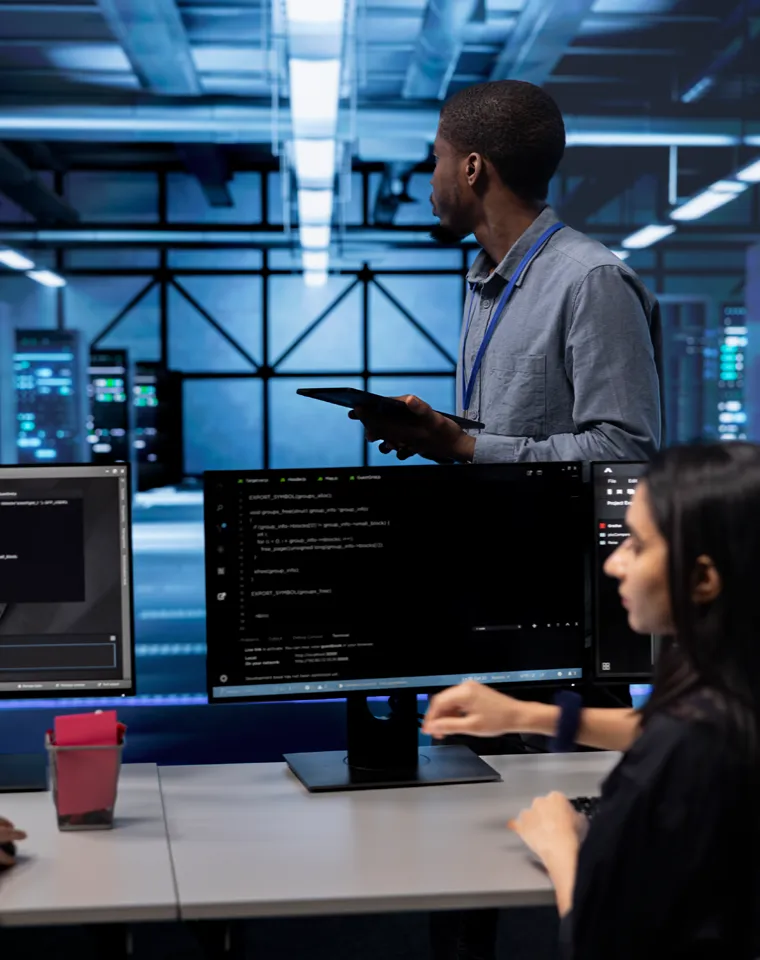 Engineers working on Flask microservice code across multiple monitors