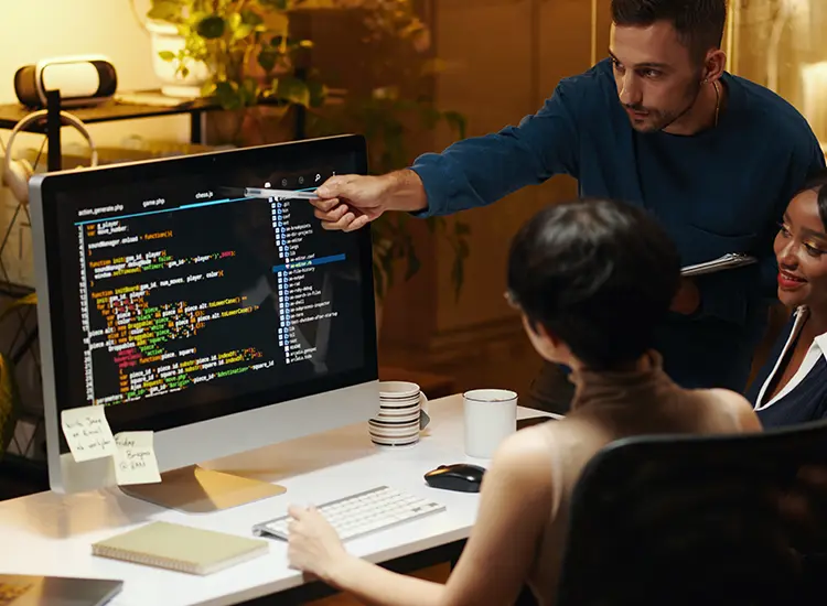 Reduce The Complexity Of Mission Critical Enterprise Software Through Infragistics Reduce The Complexity Of Mission Critical Enterprise Software: developer pointing at code on a monitor during a review